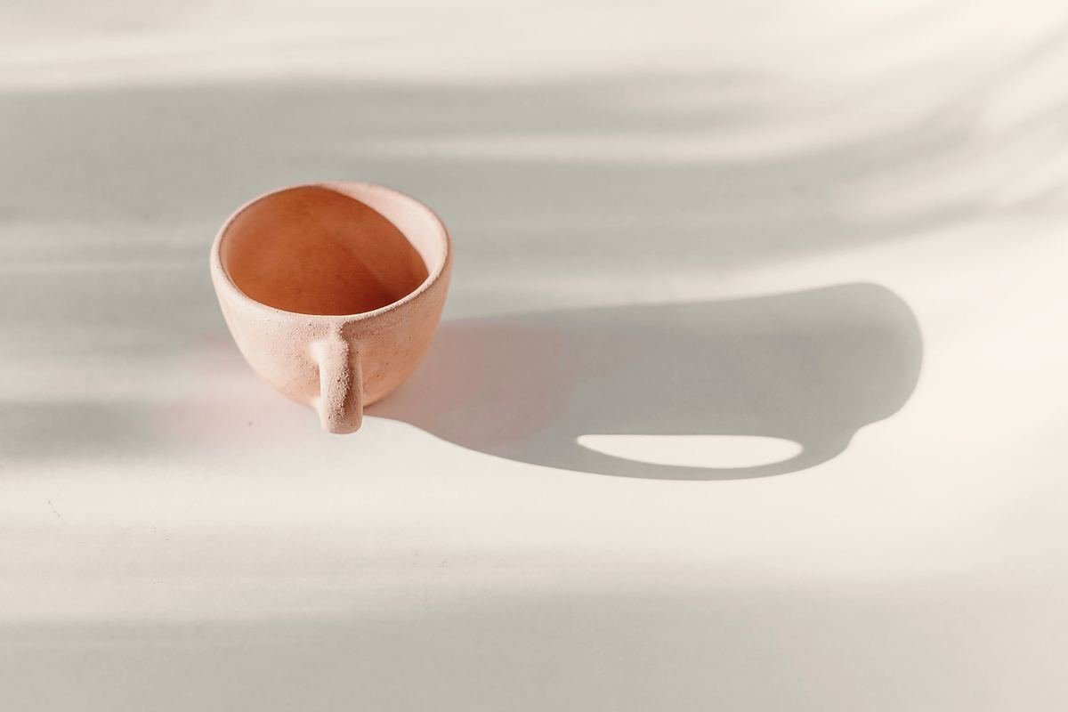 A ceramic cup casting a long shadow